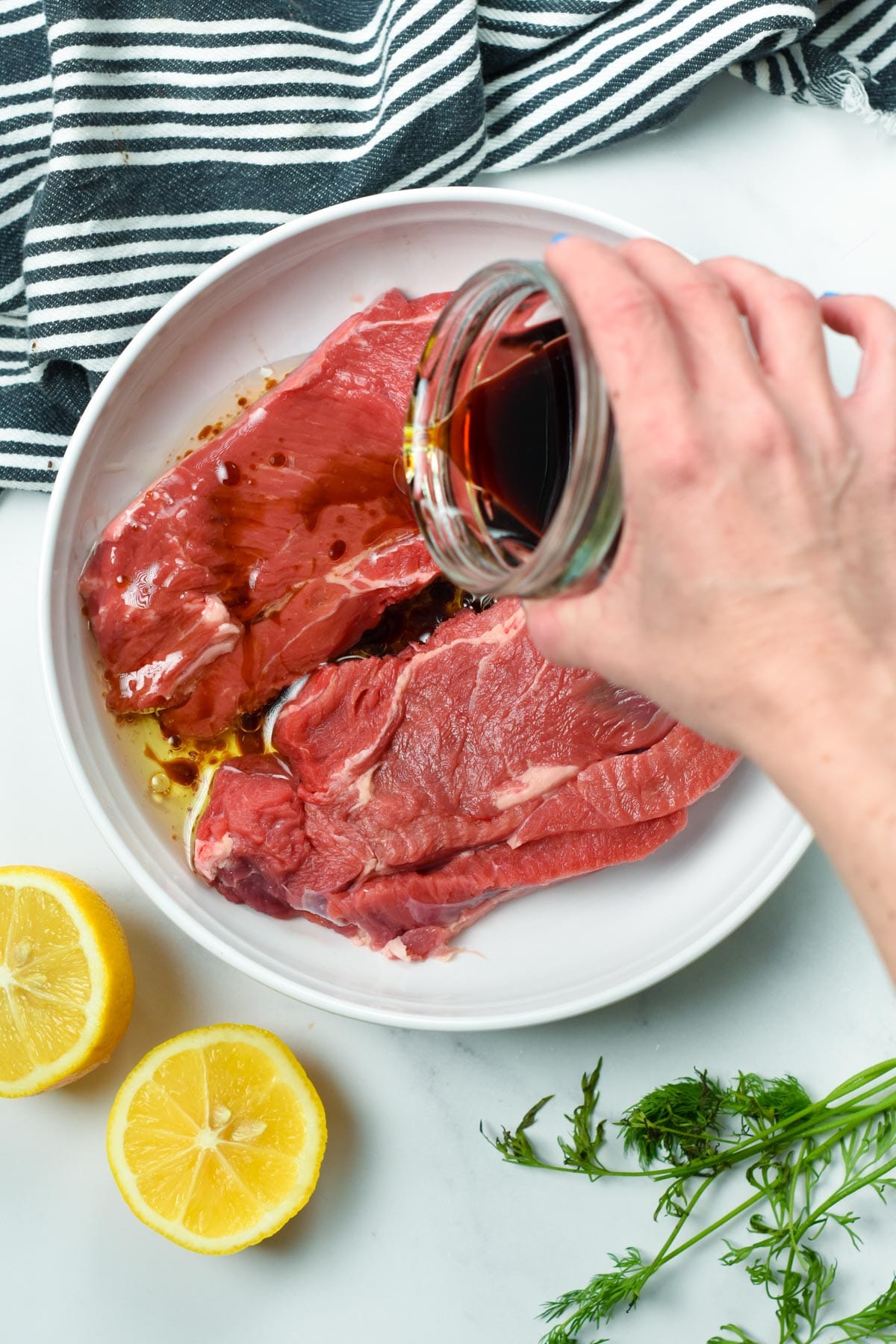 Pouring the 3 ingredient Steak Marinade on uncooked meat.