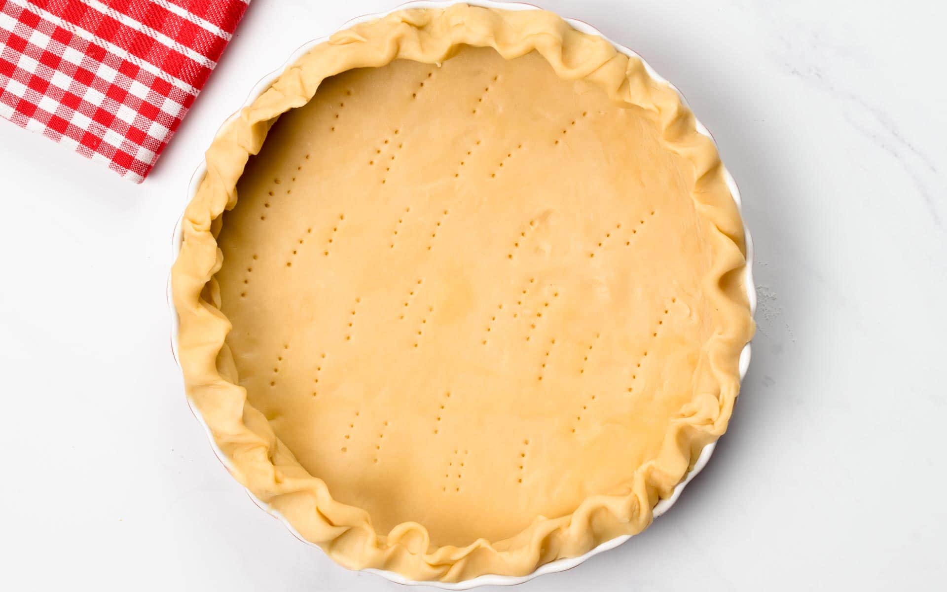 3 ingredient Pie Crust pricked on a pie pan before cooking it.