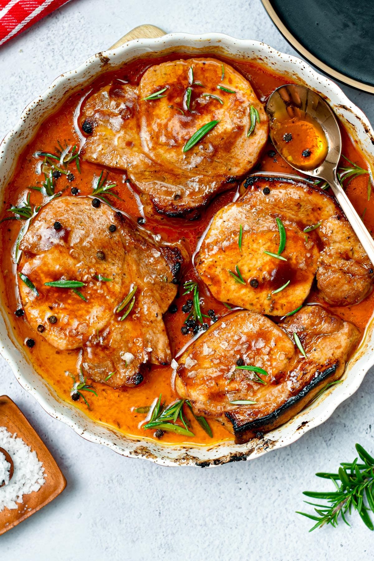 4 ingredient Oven Baked Pork Chops on a large baking dish, decorated with rosemary.