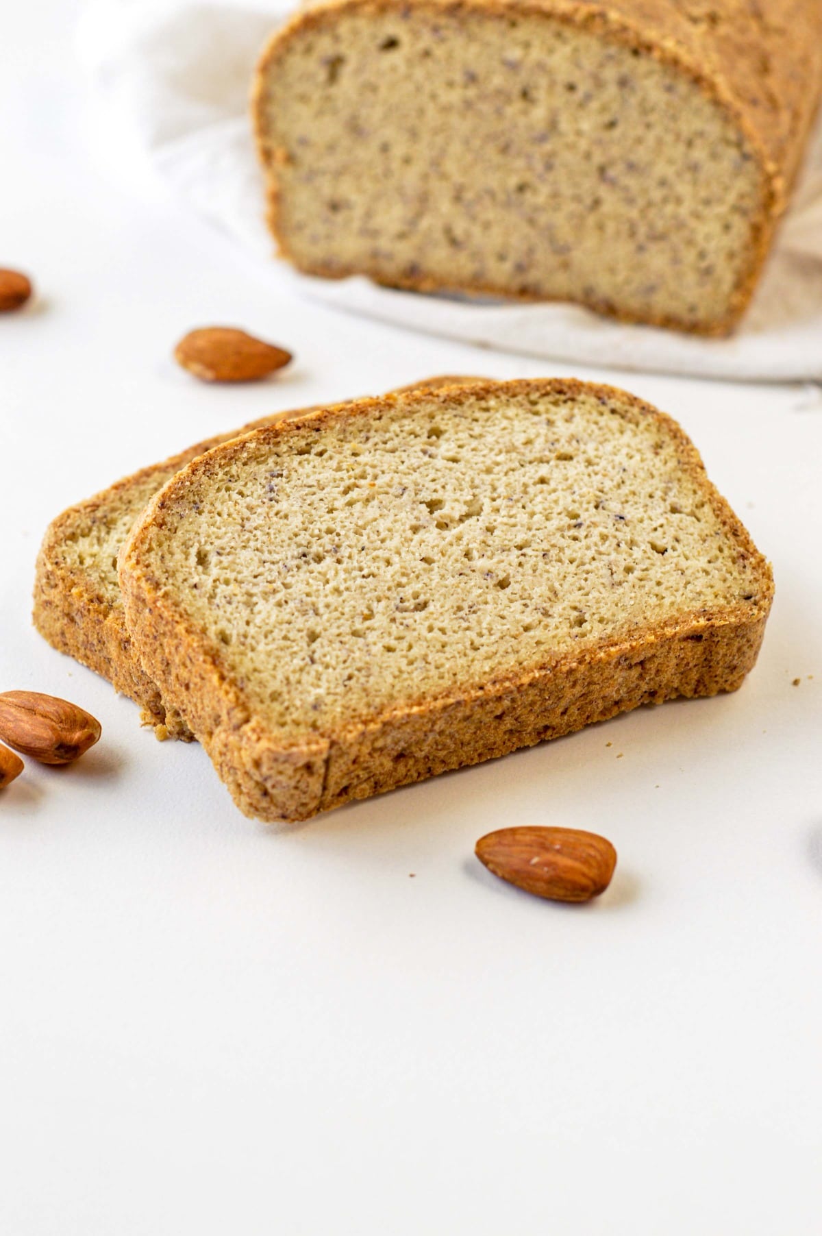 Two slices of Almond Flour Bread in front of the full loaf.