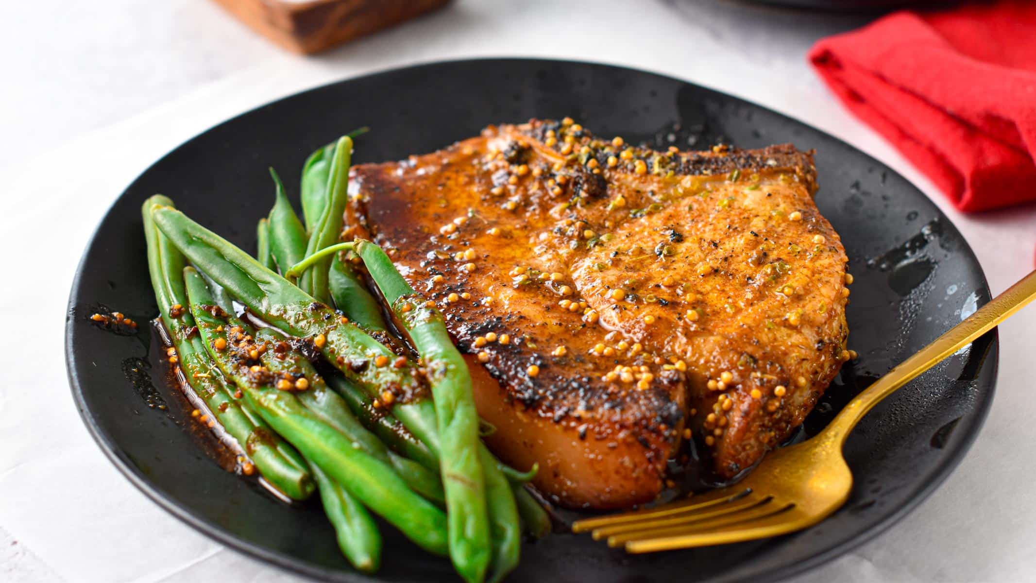 a plate with a broiled pork chop and green beans on the side