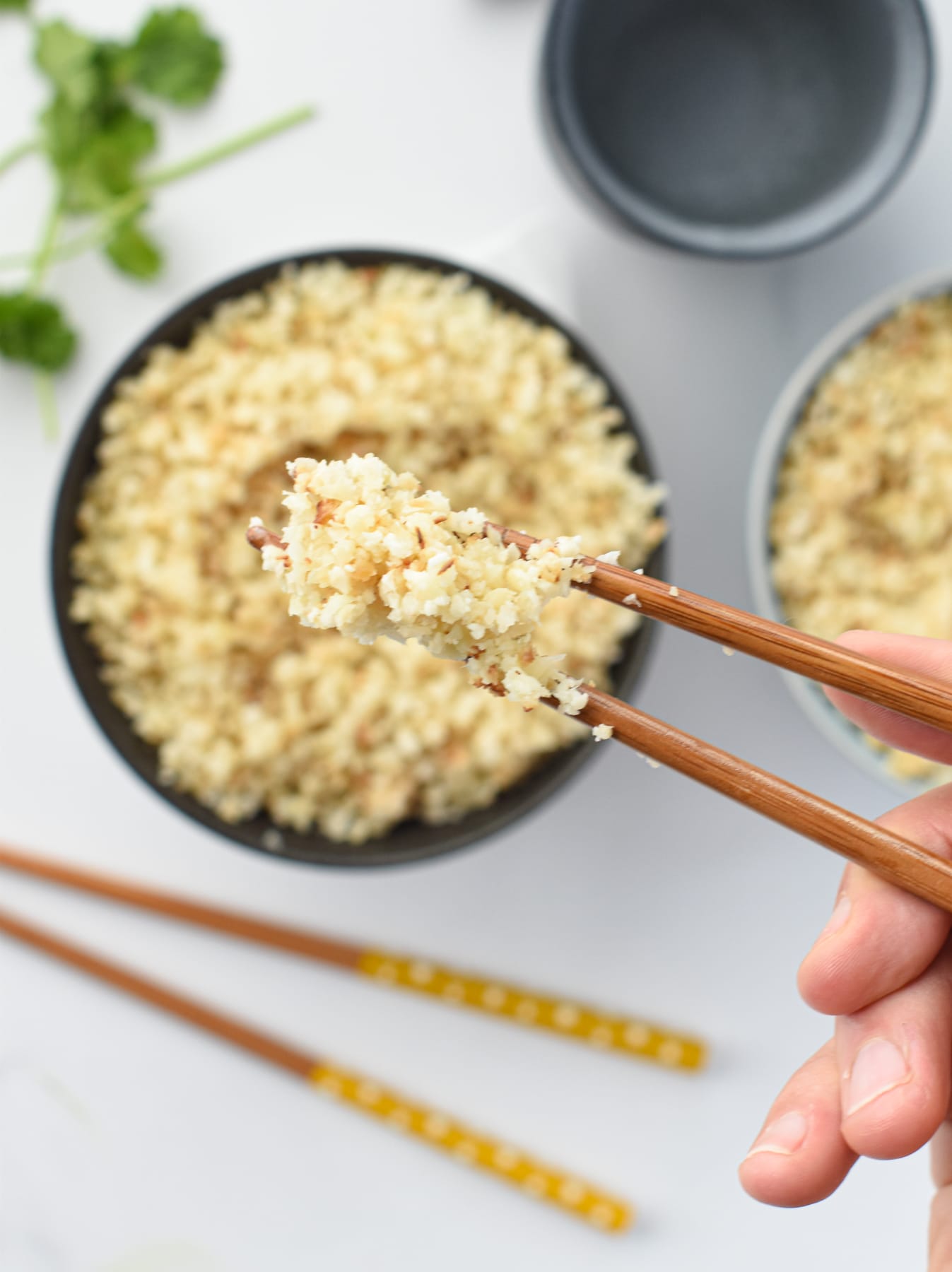 Cauliflower Rice served with chopsticks above the bowl.
