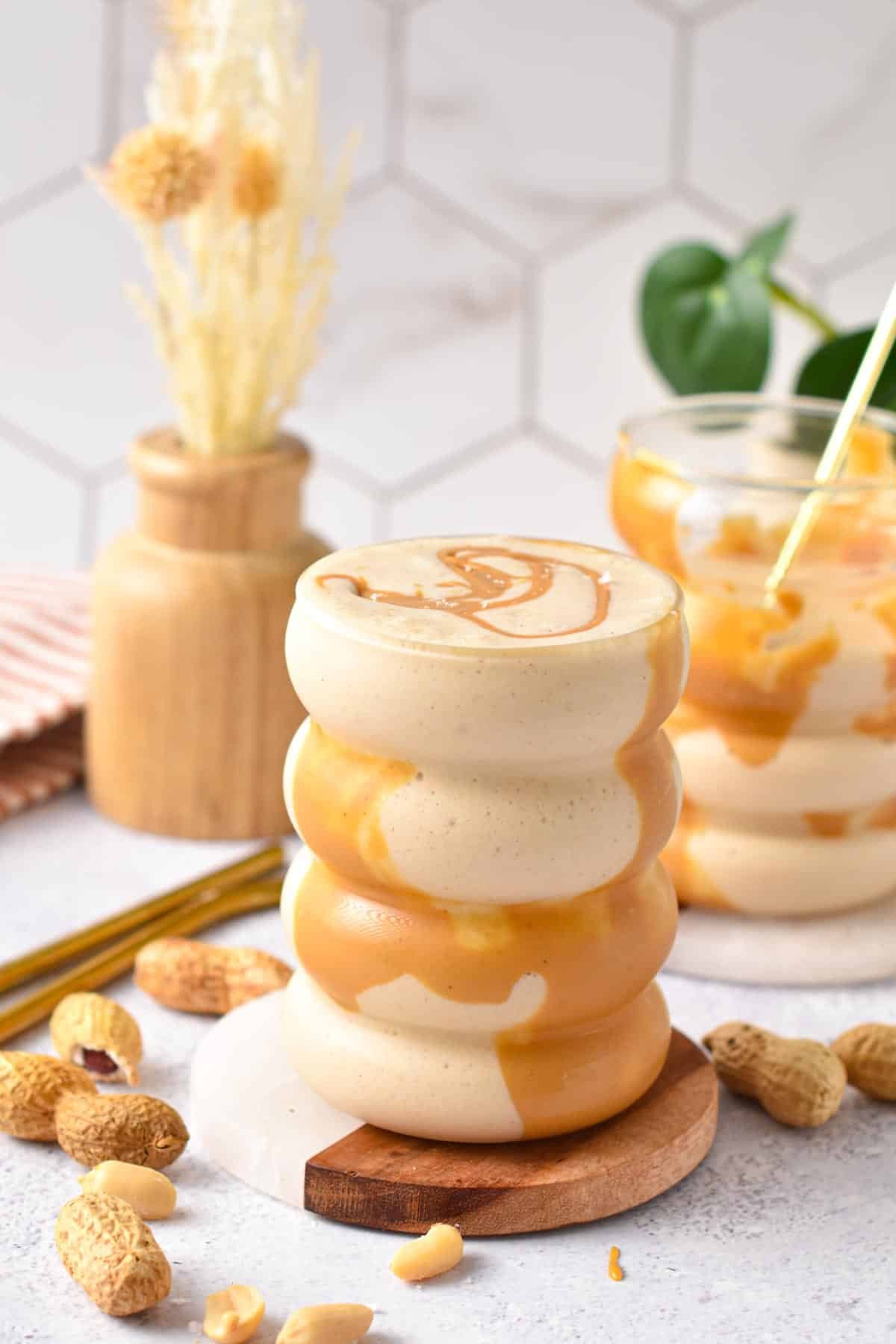 A glass filled with peanut butter cauliflower smoothie and a drizzle of peanut butter on top.