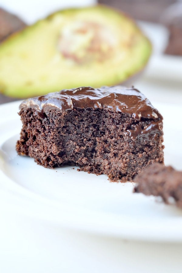 Keto Avocado Chocolate Cake slice in front of a sliced avocado.