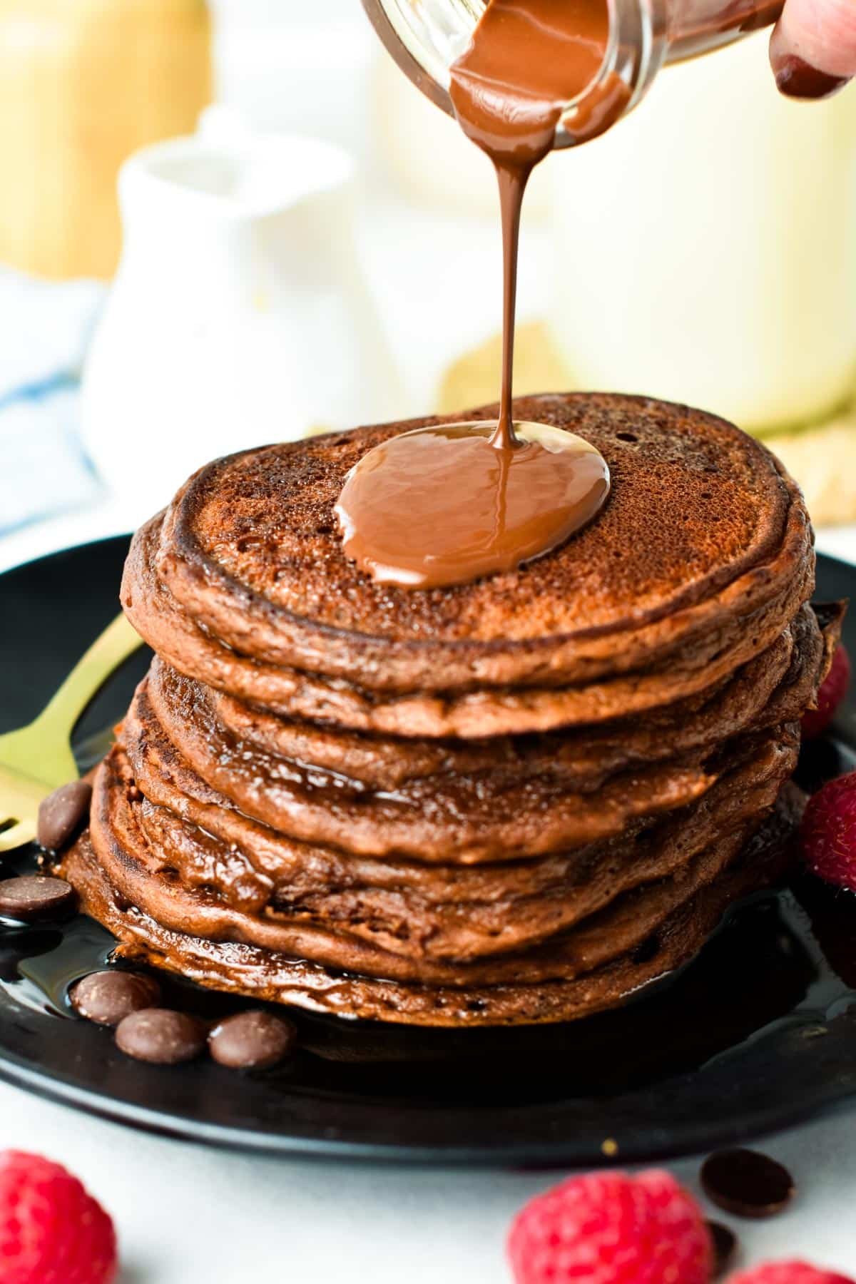 A chocolate sauce poured on a stack of chocolate protein pancakes.