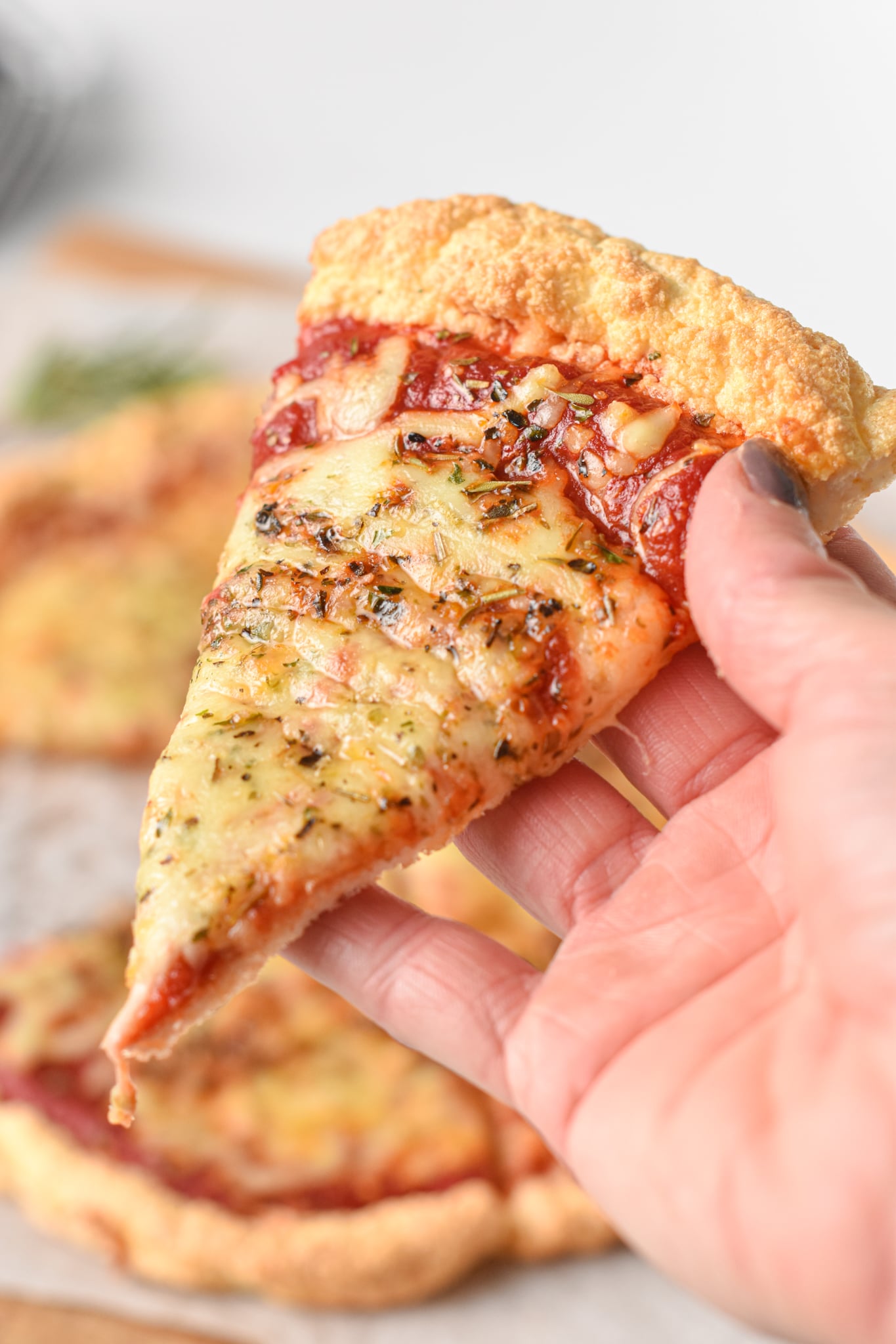 Holding a slice of Keto Cloud Bread Pizza n my hand
