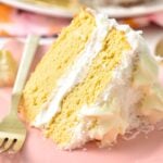 a slice of two layer This Coconut Flour Cake is a moist, fluffy gluten-free, low-carb birthday cake for coconut lovers. You will love its light coconut crumb filled with vanilla frosting. with white frosting and shredded coconut around