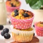 two coconut flour blueberry muffins stacked together with pink dotted paper liner