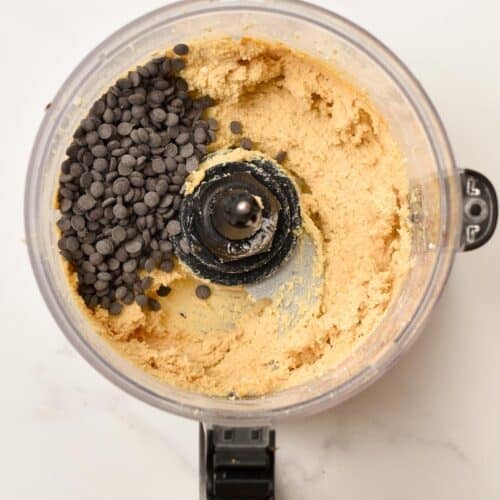 A food processor bowl filled with cottage cheese cookie dough and chocolate chips not blended.