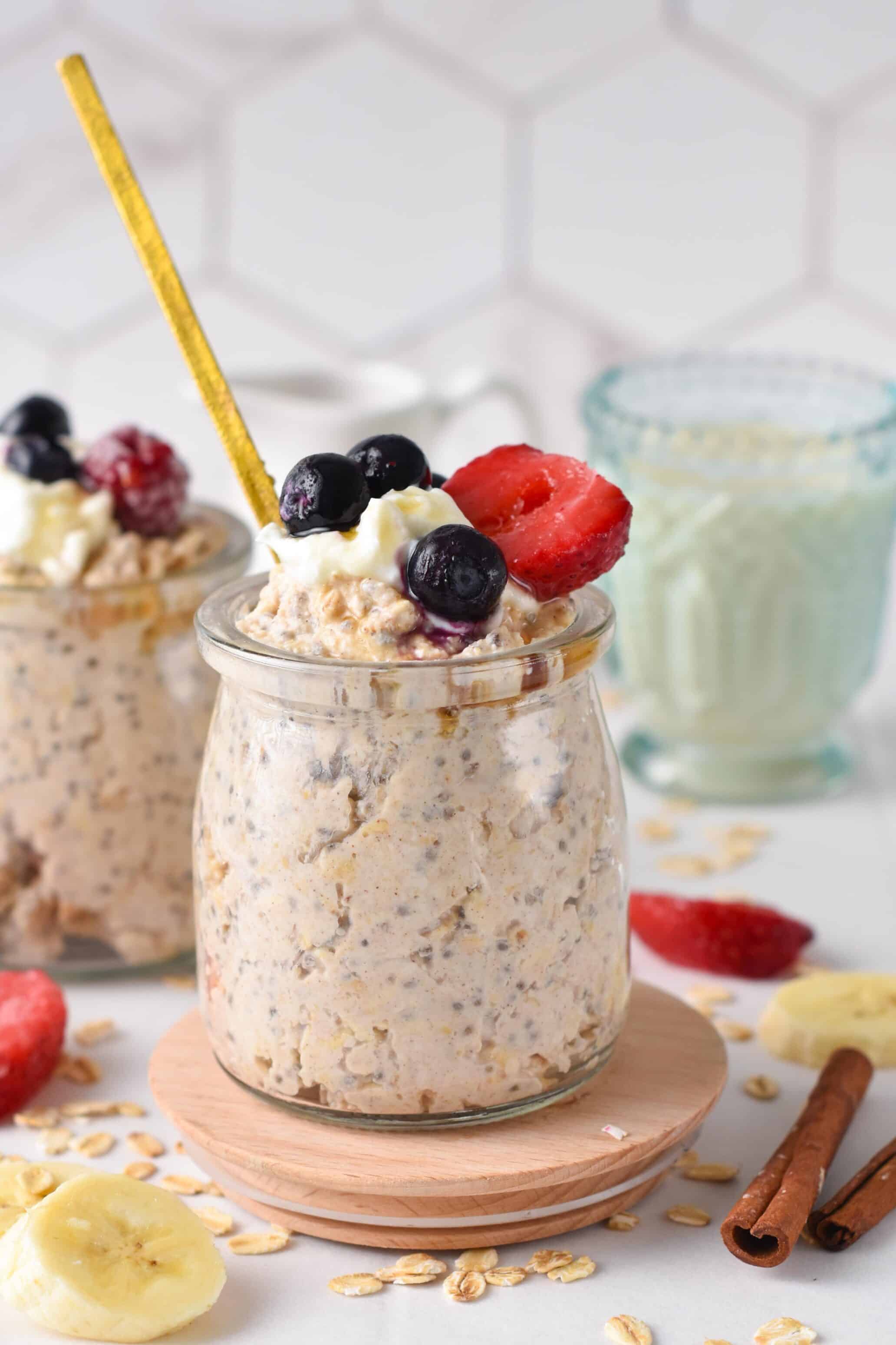 A glass mason jar filled with a cottage cheese overnight oats with berries on top