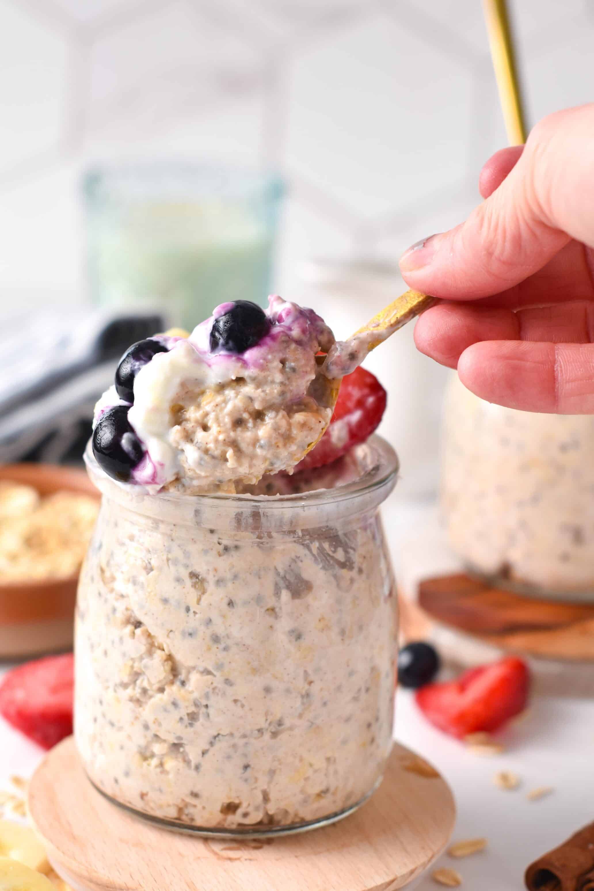 a spoon digging into a glass mason jar of protein overnight oats