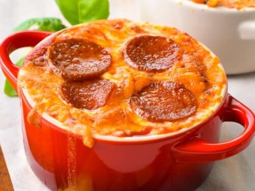 a red ramekin with baked cottage cheese, grated grilled mozzarella and pepperoni slices
