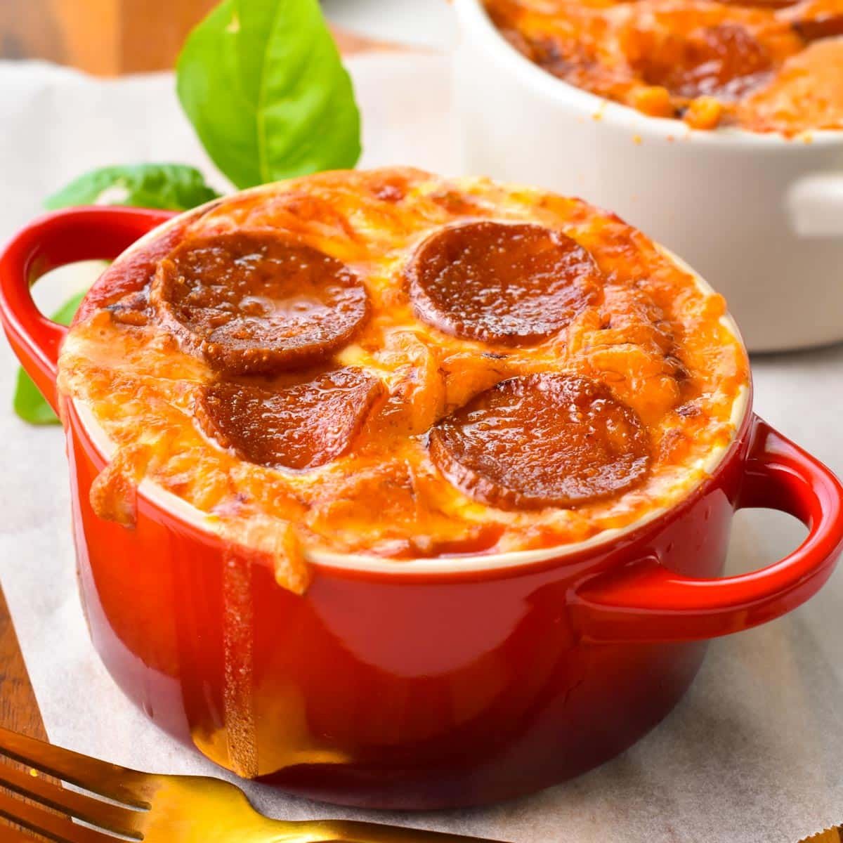 a red ramekin with baked cottage cheese, grated grilled mozzarella and pepperoni slices