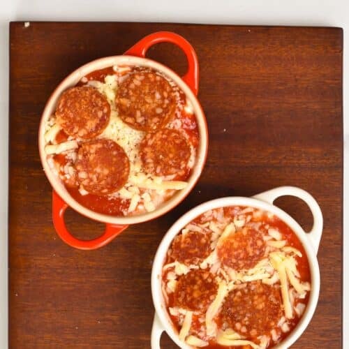 a picture from the top of two ceramic ramekins filled with cottage cheese, grated mozzarella, pepperoni slices.