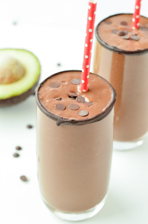 Two glasses of chocolate avocado smoothie with red paper straws.