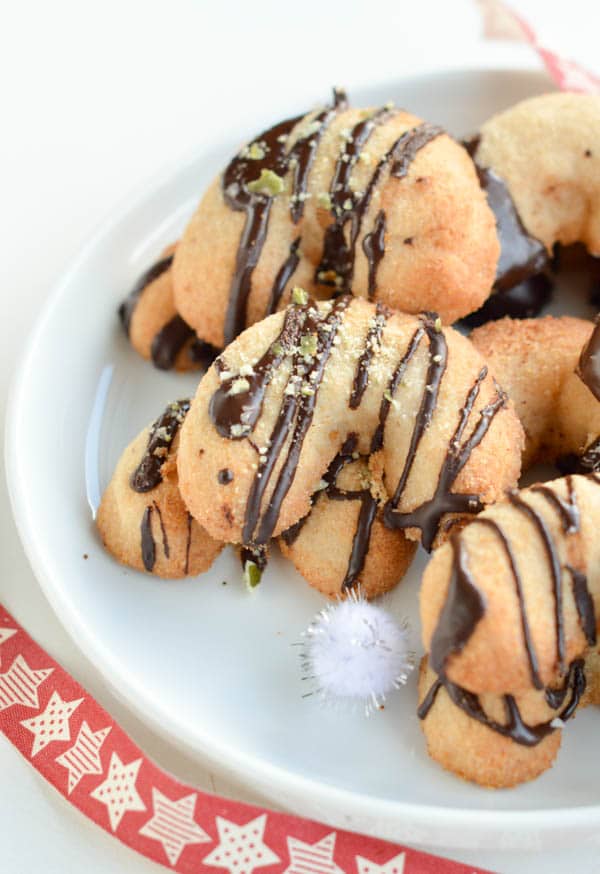 Sugar-Free Coconut Flour Cookies in a crescent shape on a white plate and decorated with a  drizzle of chocolate.