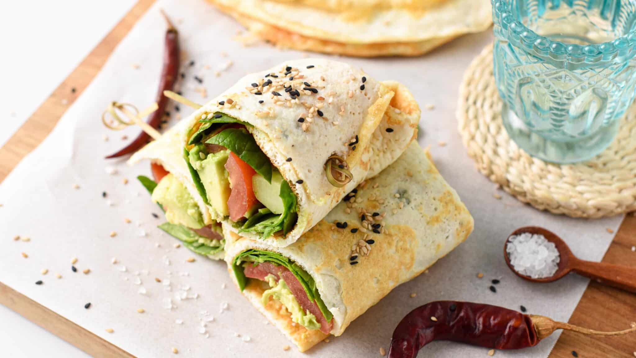Egg White Wraps filled with avocado, lettuce, and tomatoes, stacked on a chopping board 