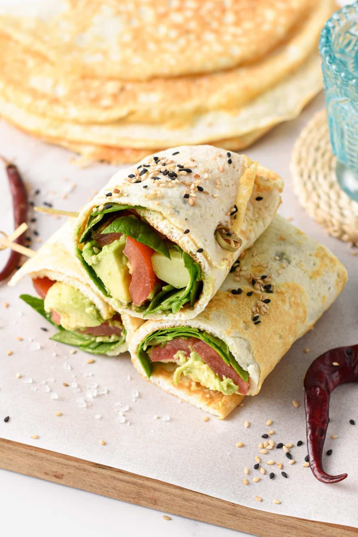 Egg White Wraps filled with vegetables on a wooden chopping board lined with parchment paper.