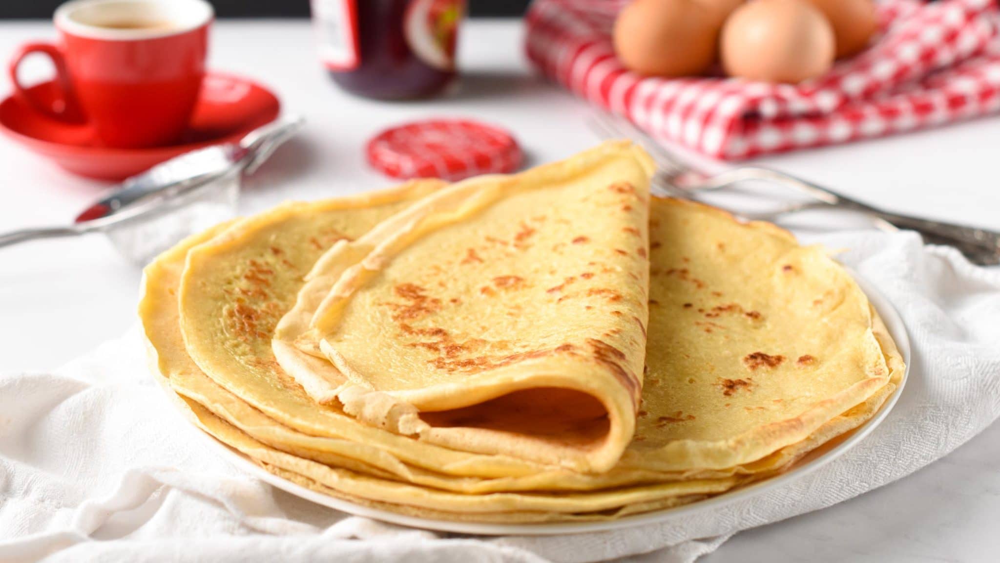 French Crepes on a plate on a breakfast table with the last one folded in half.