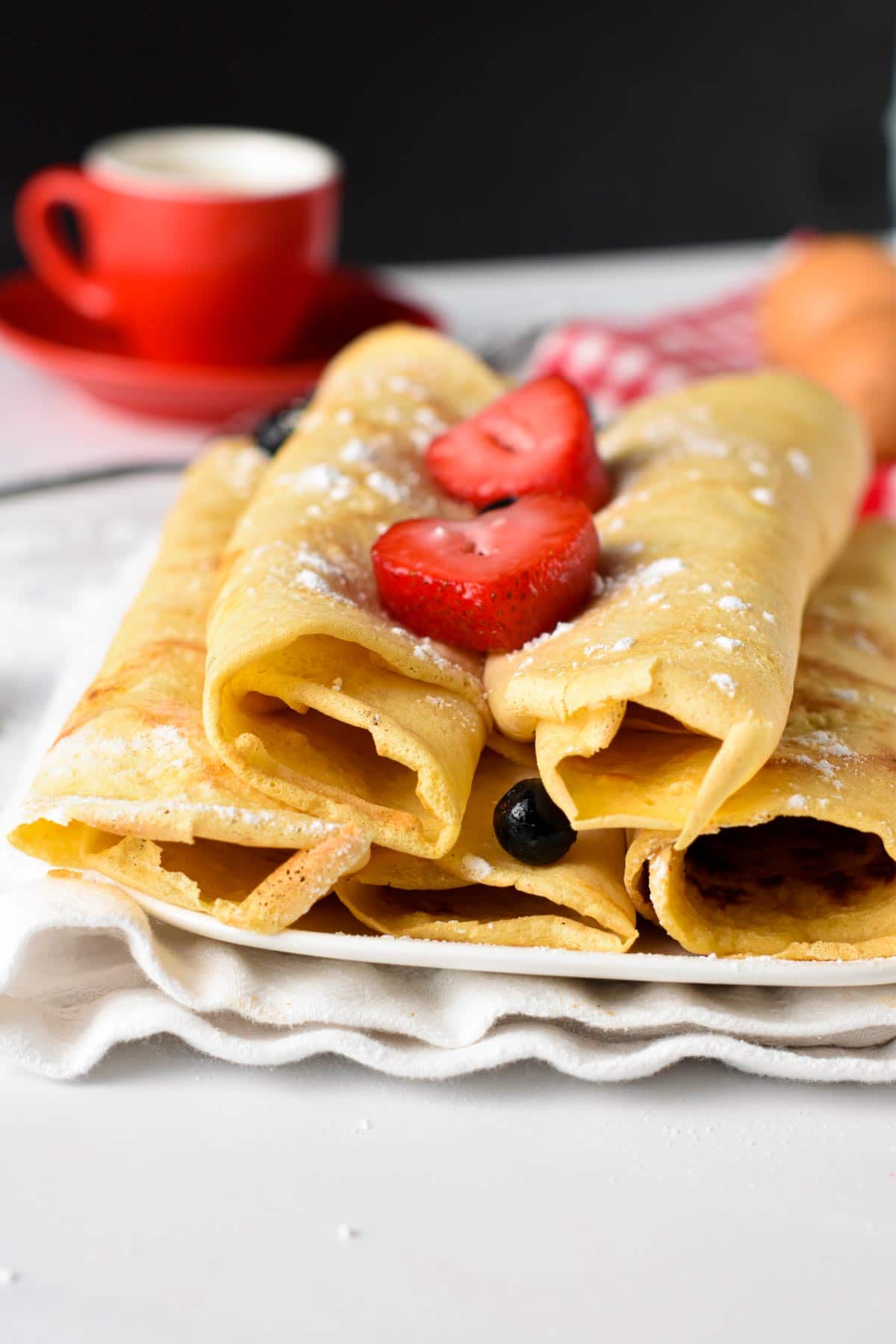 Gluten-Free Crepes rolled and stacked on a plate.