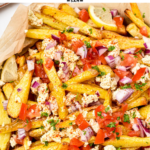 These homemade Greek Fries are crispy baked fries topped with a drizzle of lemon juice and loads of delicious Greek cuisine flavors from feta cheese, red onions, tomatoes and Parsley.