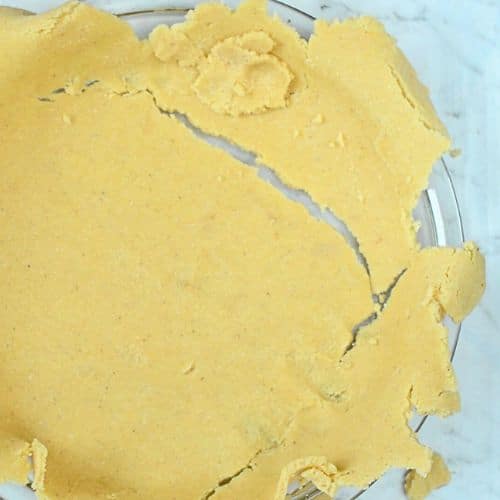 Placing Keto Pumpkin Pie crust in the pan.