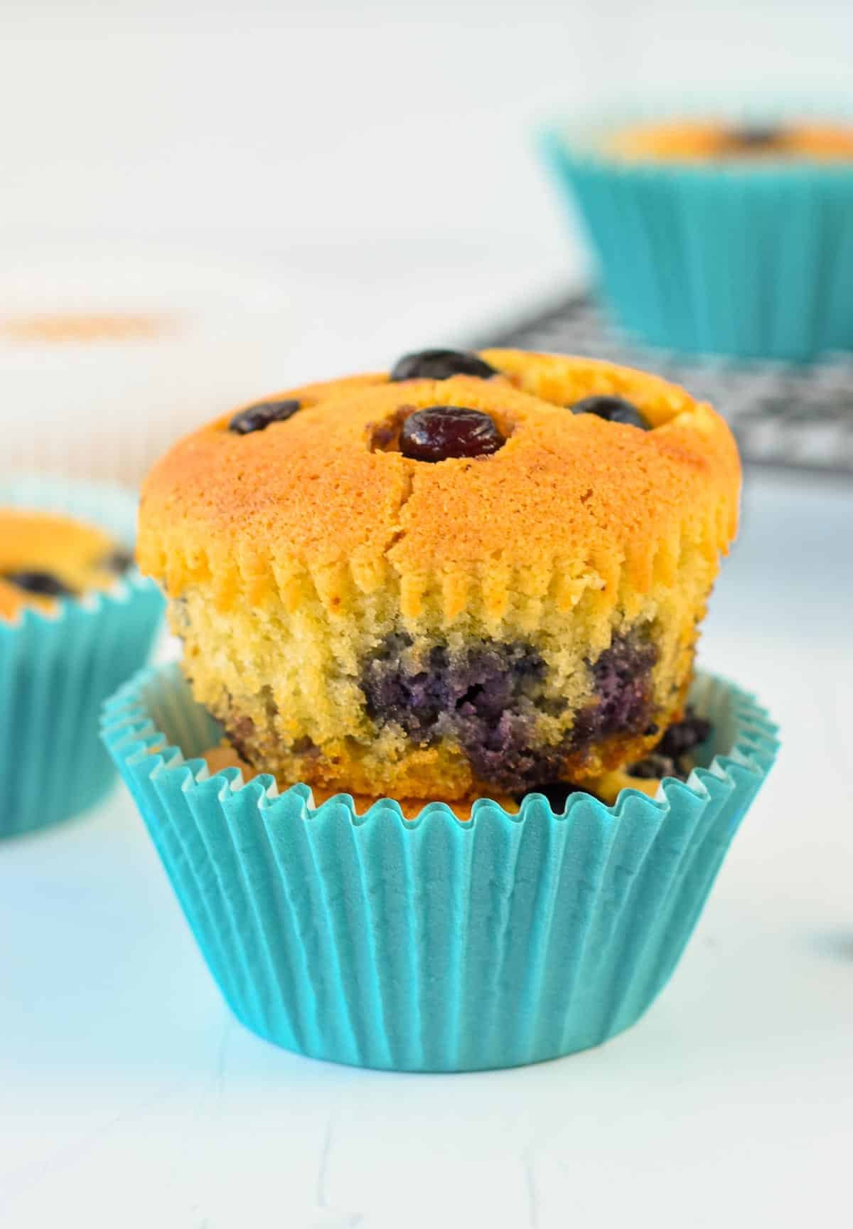 A stack of two almond flour blueberry muffins with blue muffin cases.