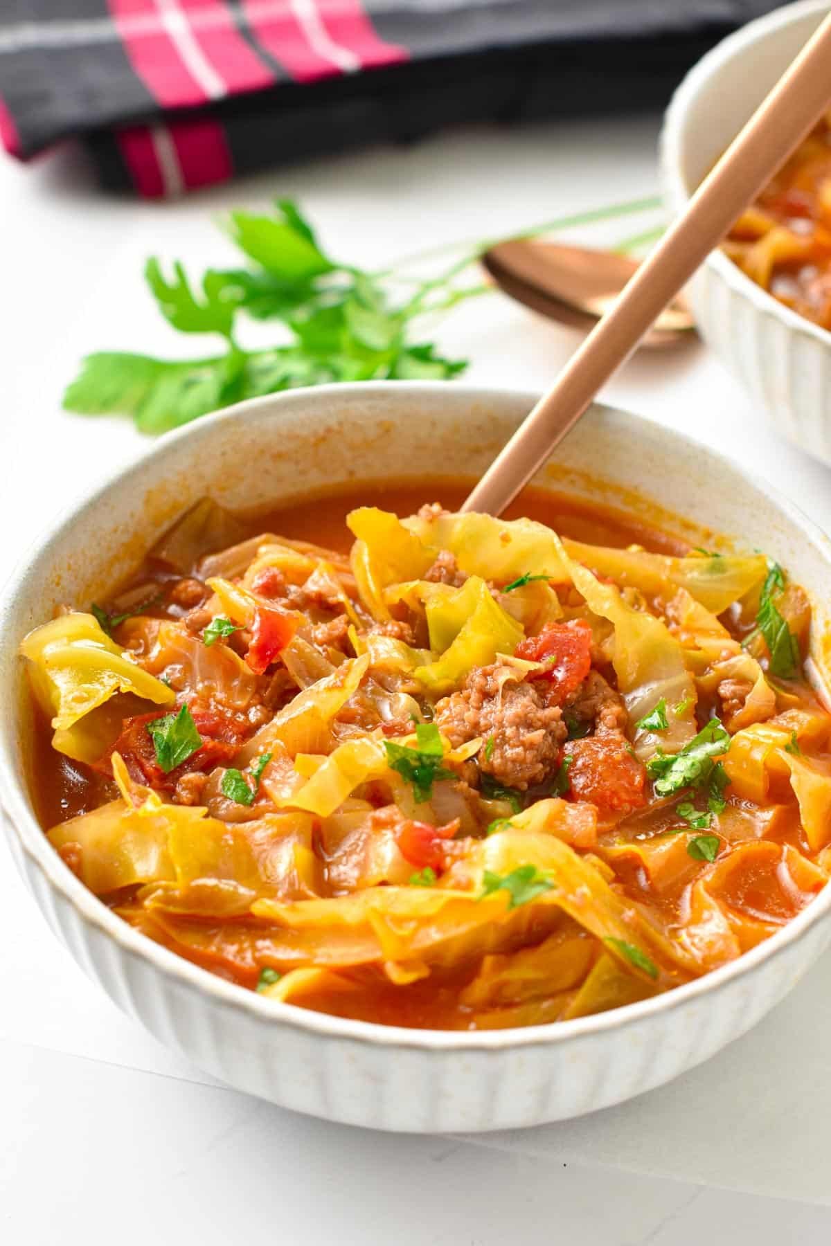 a bowl filled with low-carb cabbage soup made with green cabbage, beef broth, ground beef and celery and topped with fresh parsley