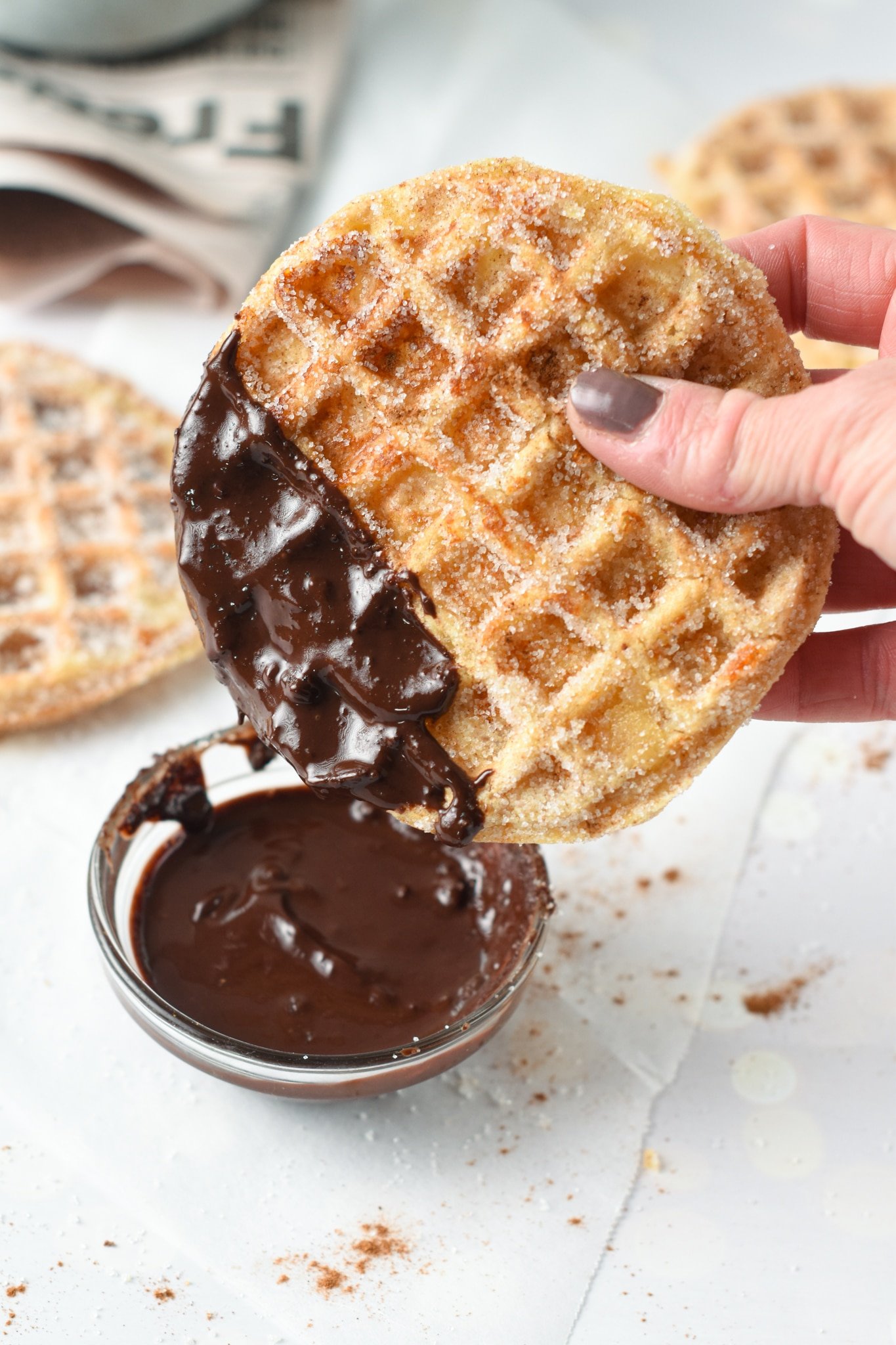 Keto Churro Chaffle dipped into chocolate.