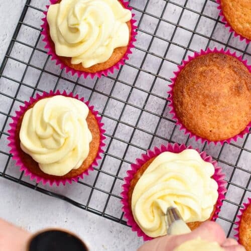 a pipping bag hold by a hand, pipping keto cupcakes with keto cream cheese frosting