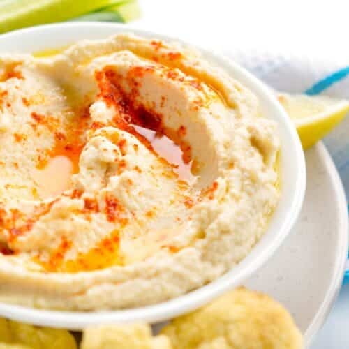 a bowl filled with keto hummus topped with olive oil and paprika