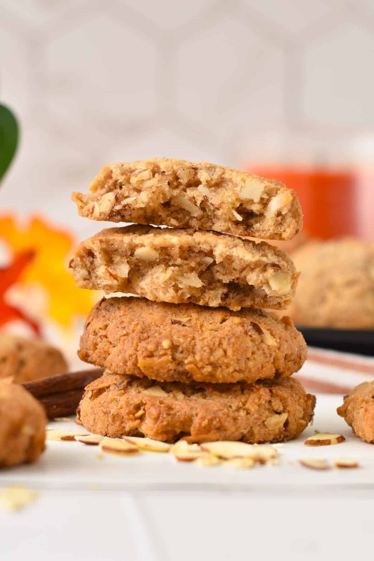 A stack of keto oatmeal cookies with one cookie broken in half showing the soft, chewy texture inside the cookie.