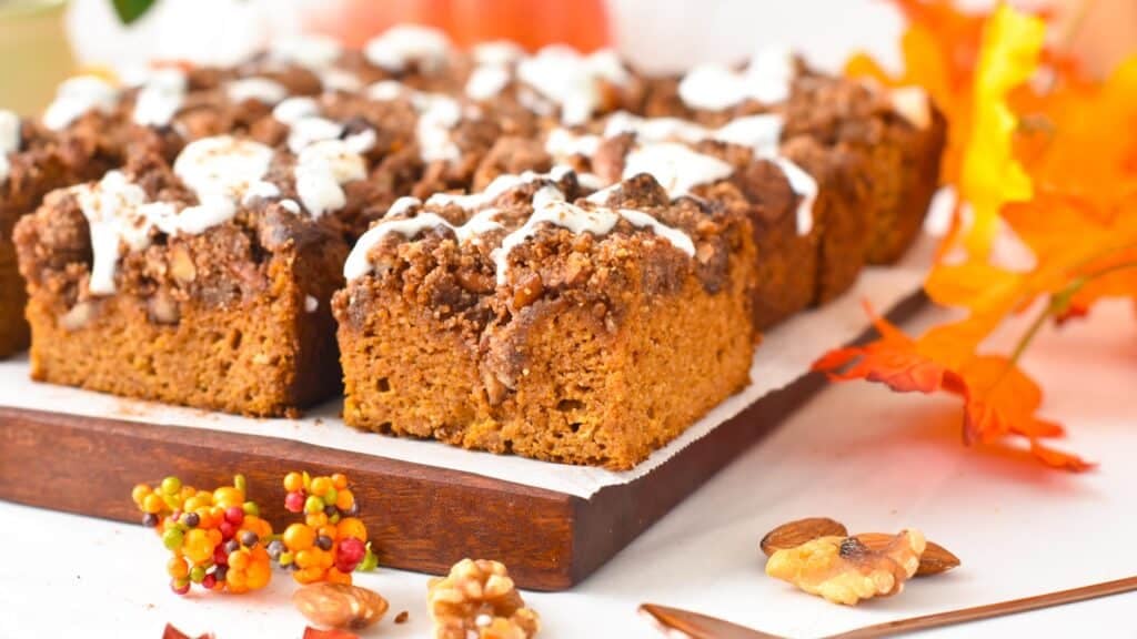 Slices of almond flour pumpkin cake topped with a pecan crumble and drizzle of yogurt