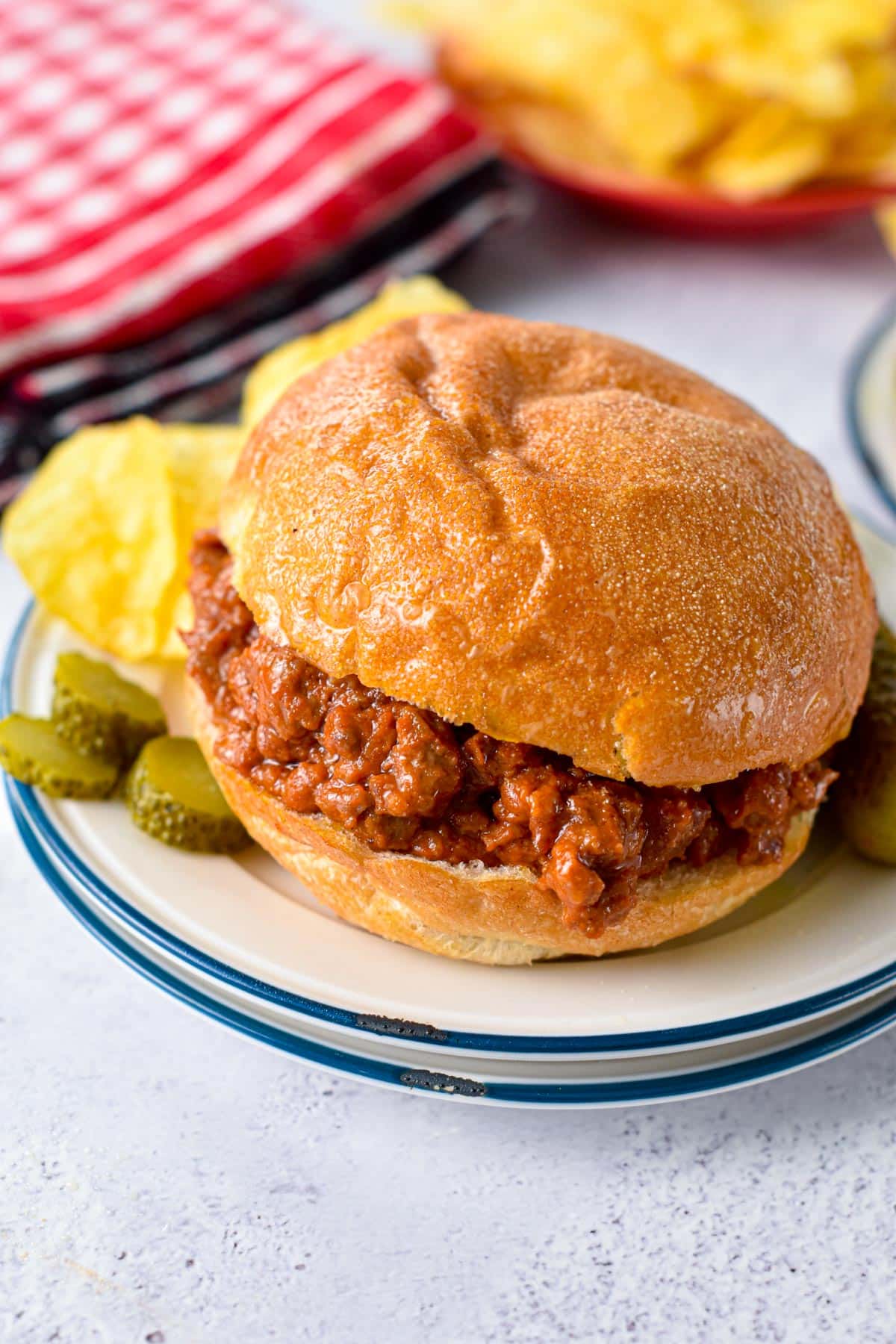 A low-carb bun filled with low-carb sloppy joe filling and gherkins on the side.