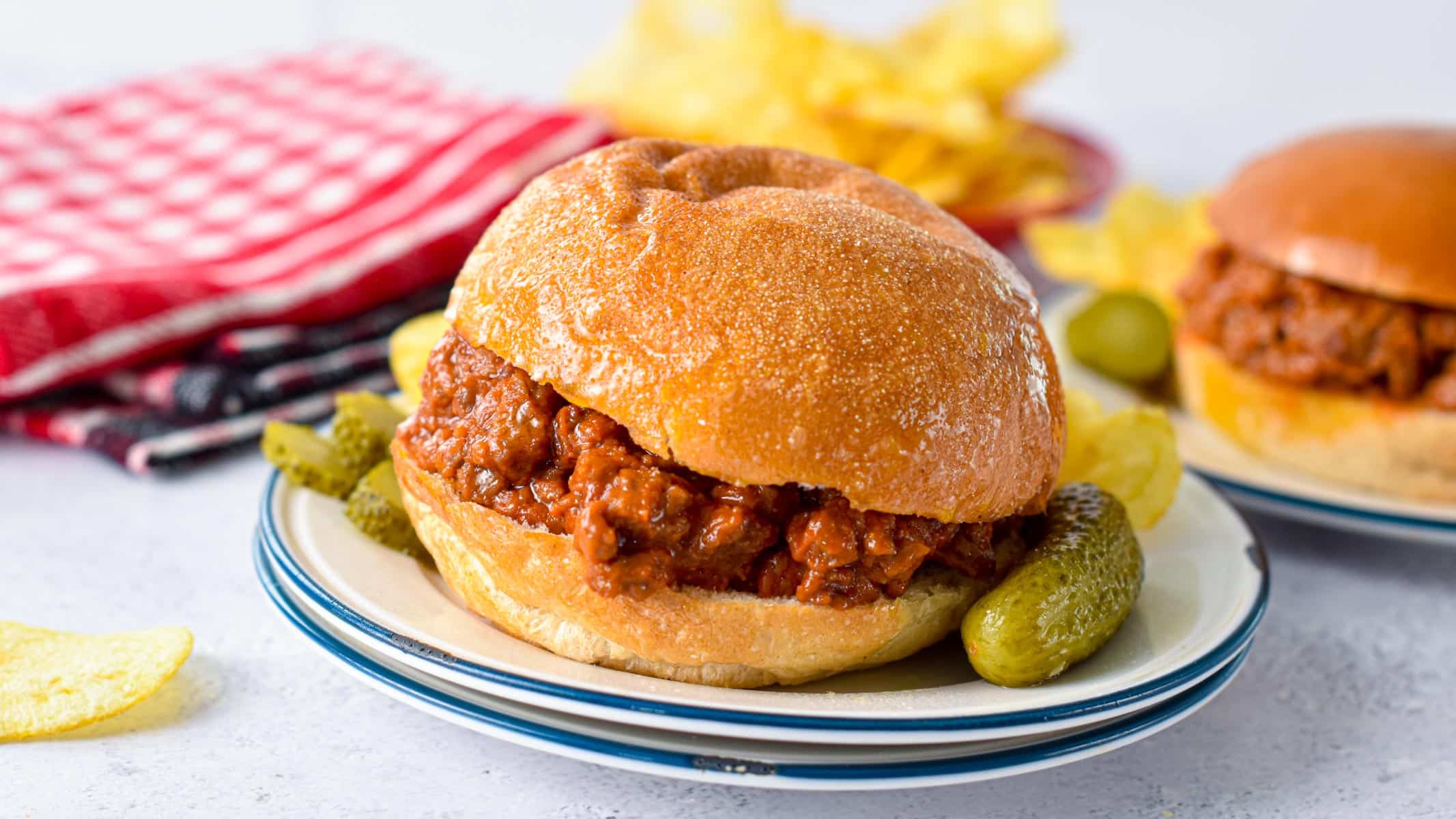 A low-carb bun filled with low-carb sloppy joe filling and gherkins on the side.