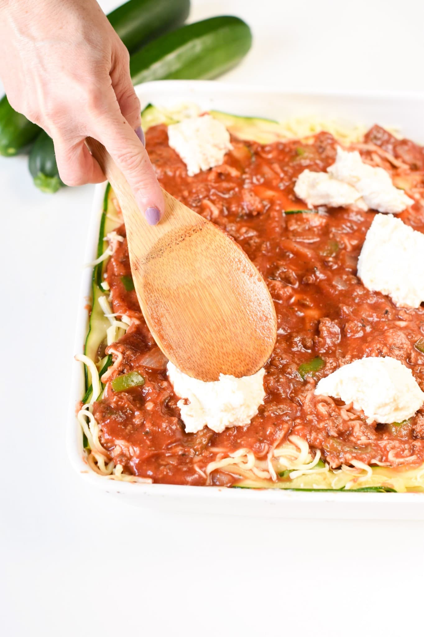 Spreading cheese on the Zucchini Lasagna layers.