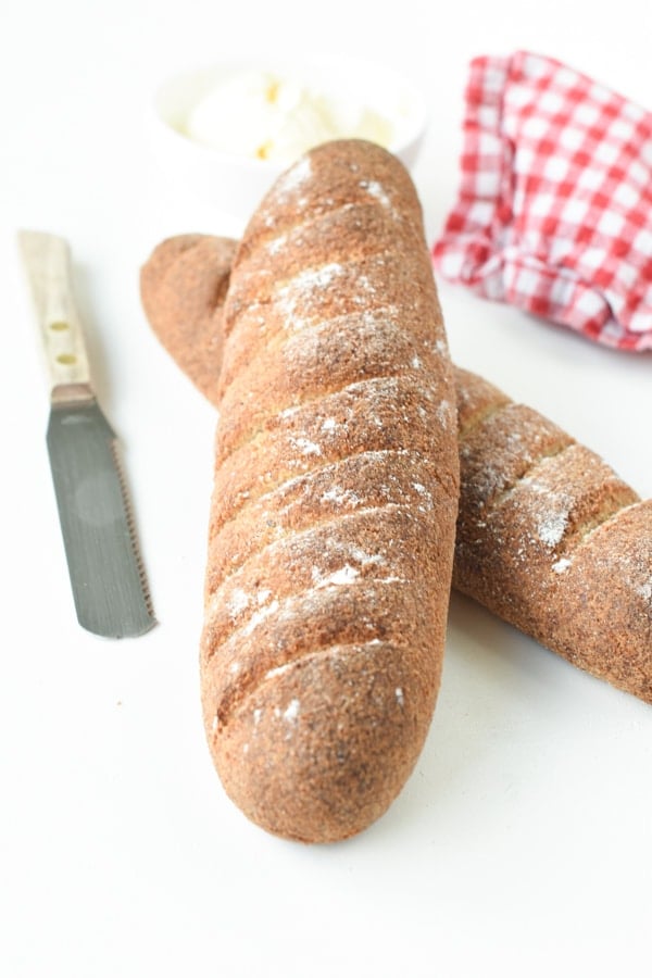 Two Keto baguettes crossed next to a small bread knife.