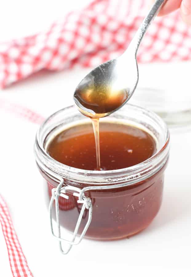 Keto simple syrup in a small jar, dripping from a spoon.