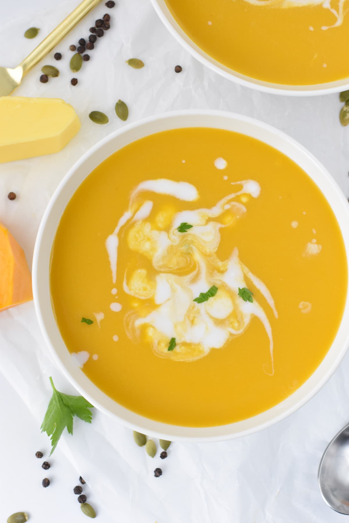 A bowl of Low-carb Pumpkin Soup decorated with cream and parsley.