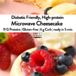a single serve microwave cheesecake on a pink plate topped with jam, raspberry, blueberries and strawberries in the background, and a black fork in the front