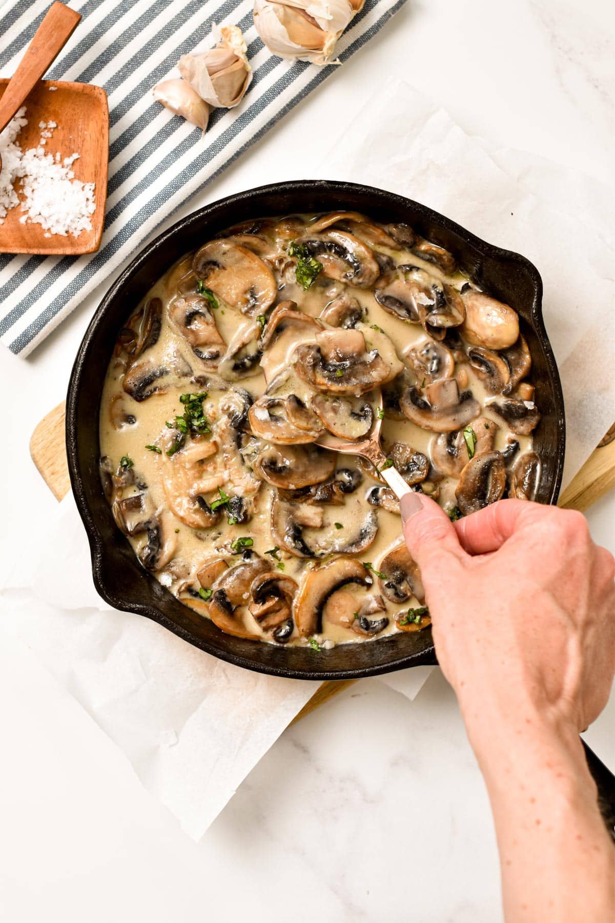 Keto Mushroom Sauce in a cast-iron pan on a wooden board next to a kitchen towel.