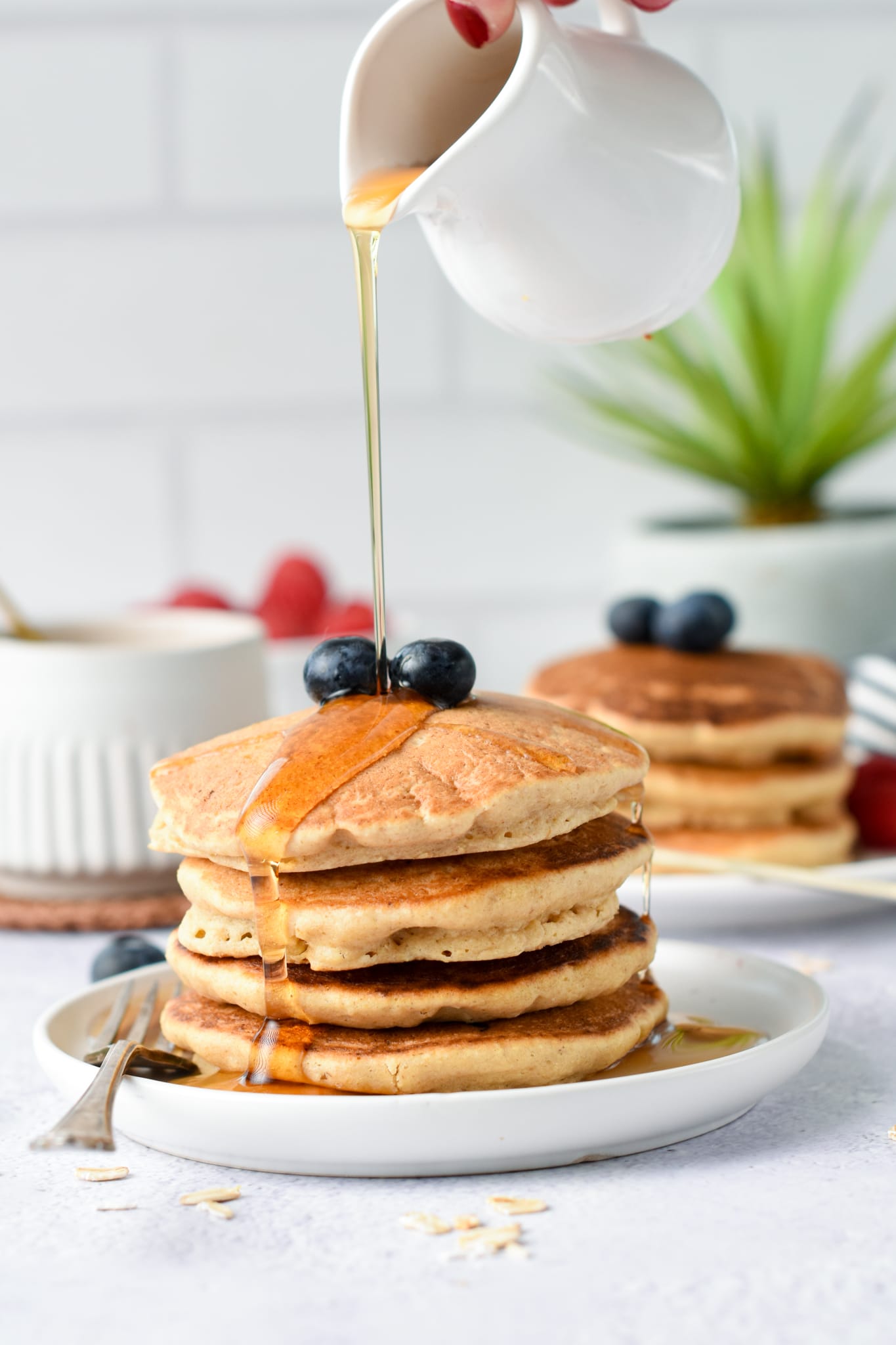 Pouring maple syrup on Oat Flour Pancakes.
