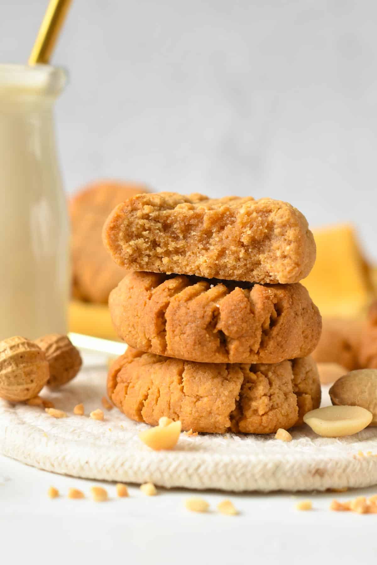 A stack of three peanut butter cookies with one cookie cut in half showing the crunchy texture inside.