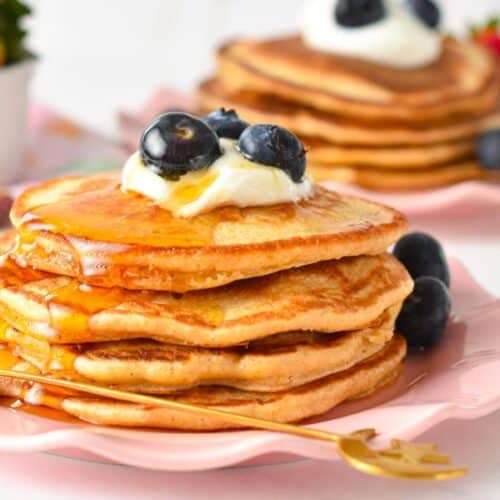 a stack of protein pancakes topped with yogurt, blueberries