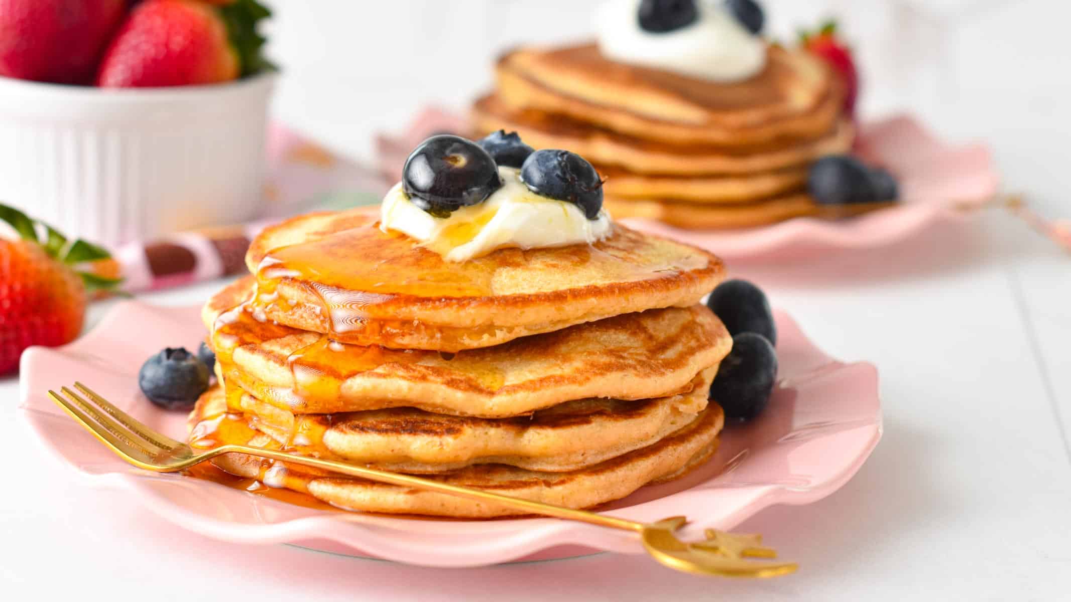 A stack of protein pancakes topped with yogurt, blueberries.