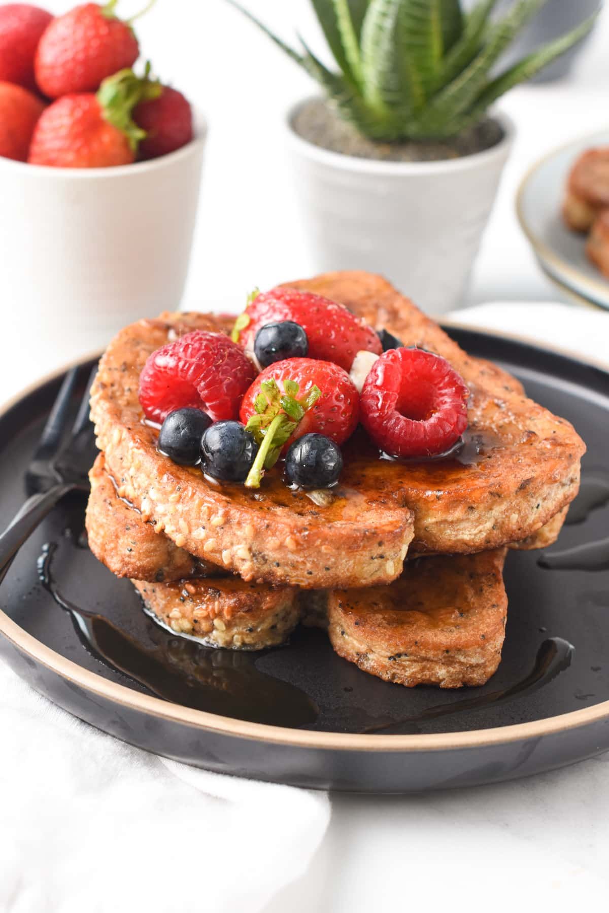 Protein French Toast on a black plate, decorated with fresh berries.