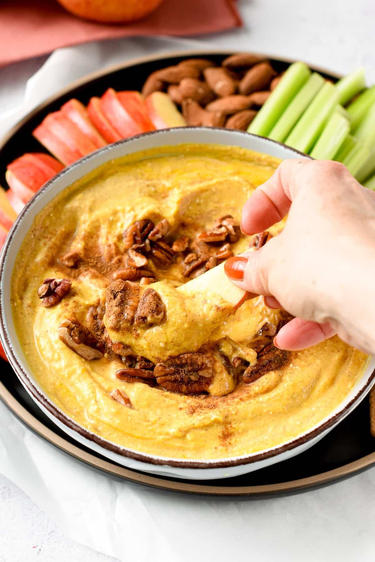 Pumpkin Cream Cheese Dip in a large bowl with cut veggies on the side.