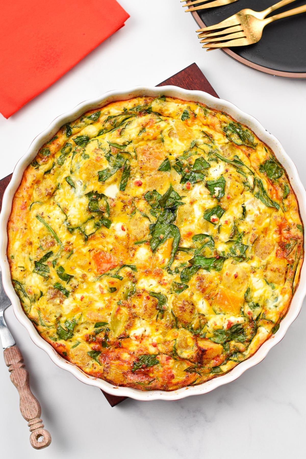 A roasted pumpkin spinach frittata in a ceramic pan, pictured from the top.