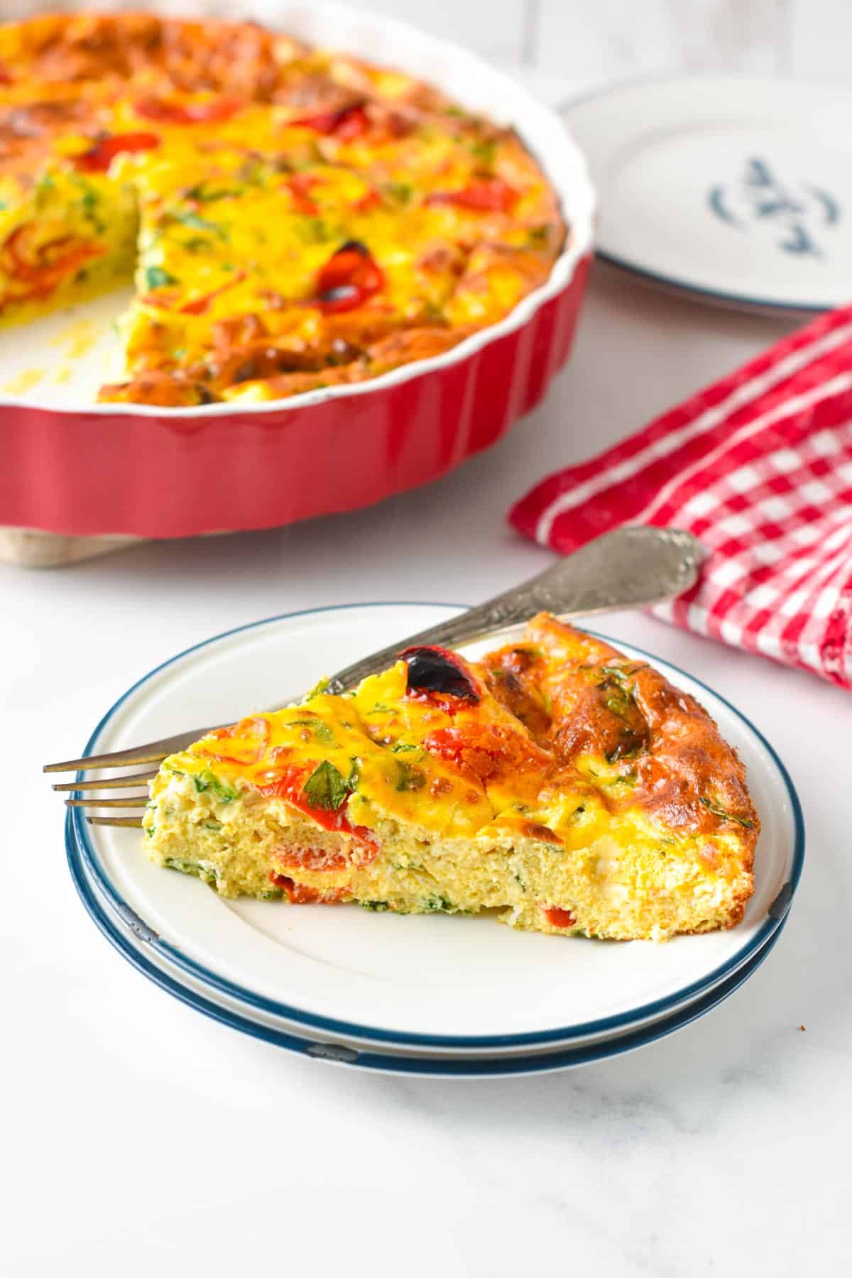 A slice of ricotta frittata filled with spinach and roasted red bell pepper.