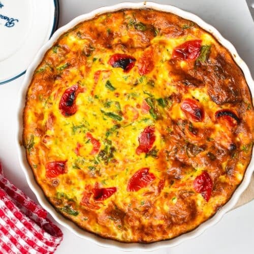 a pie plate filled with ricotta frittata, with roasted bell pepper and spinach
